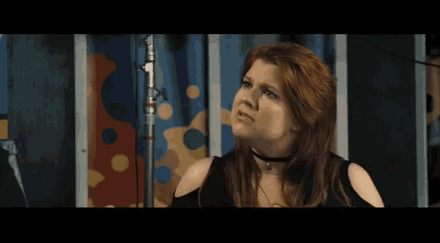 a woman with red hair is making a funny face in front of a colorful curtain