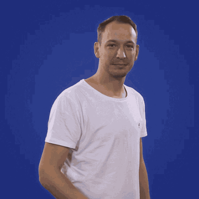a man in a white t-shirt stands in front of a blue background that says enow