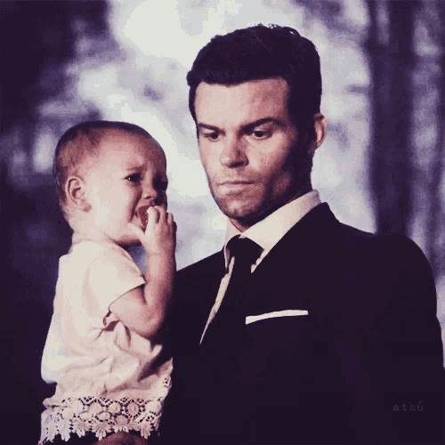 a man in a suit and tie is holding a baby in his arms