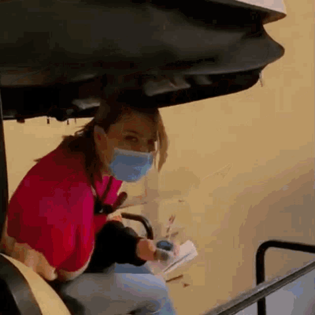 a woman wearing a mask is sitting in a chair