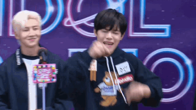 two young men are standing next to each other in front of a sign that says idol .