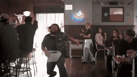 a man is dancing in a bar with a texas flag on the wall behind him