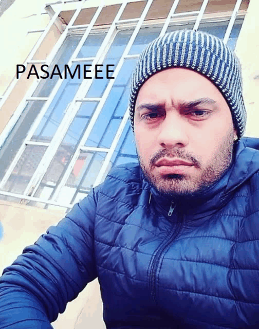 a man wearing a blue jacket and a beanie has the word pasameee on the bottom