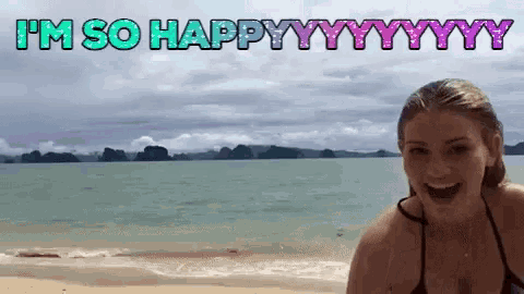 a woman in a bikini is standing on a beach with the words i 'm so happy written above her