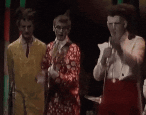 a group of men are standing next to each other on a stage in a dark room .