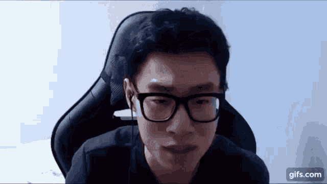 a man wearing glasses is sitting in a chair with his eyes closed .