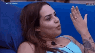 a woman is sitting on a blue couch with her hand up in the air .