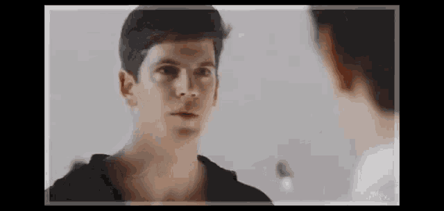 a man in a black shirt is looking at himself in the mirror .