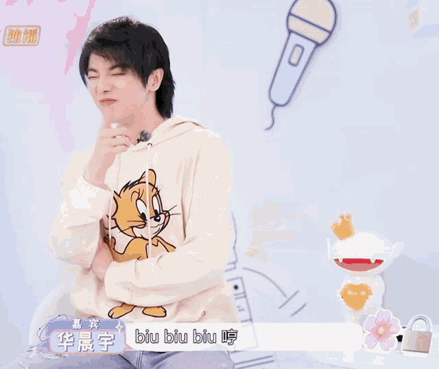 a man wearing a hoodie that says biu biu biu sits in front of a microphone
