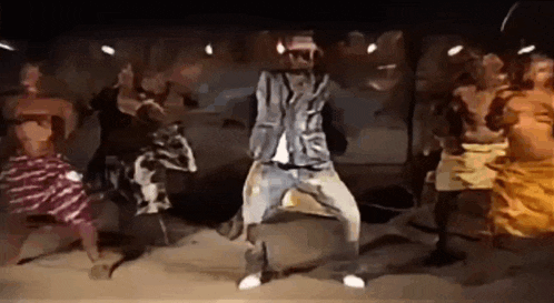 a man is dancing in front of a group of people in a dark room .