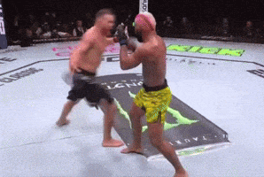 two men are fighting in a boxing ring with a monster energy logo on the floor