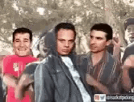 a group of men are standing next to each other and one of them is wearing a hooded jacket .