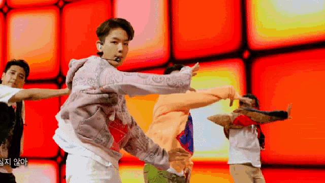 a group of people are dancing in front of a red background and one of them is wearing a purple hoodie