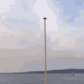 a boat is in the distance behind a pole in the water