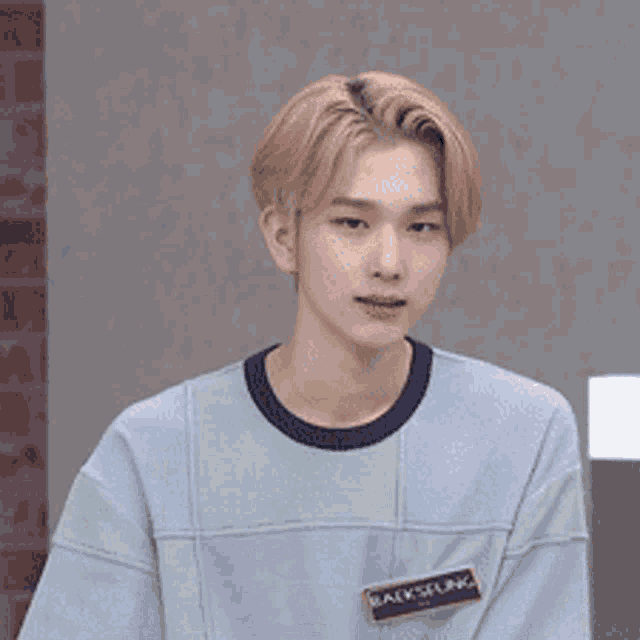 a young man wearing a light blue shirt with a black label that says walkslurk