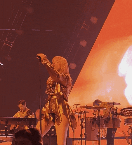 a woman singing into a microphone while a man plays a keyboard in the background