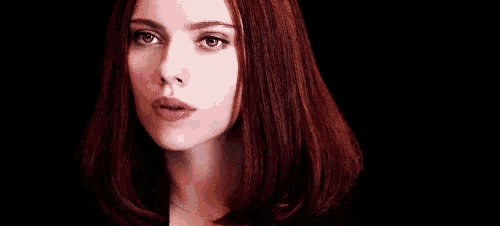 a close up of a woman 's face with red hair .