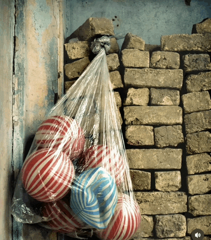 a plastic bag filled with red and white striped balls hangs on a brick wall