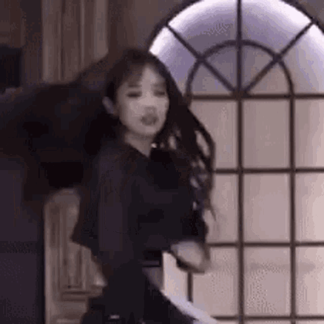 a woman is dancing in a room in front of a window .