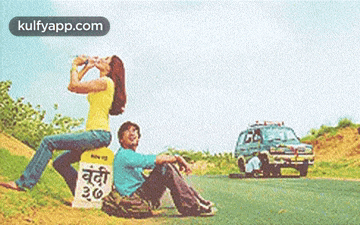 a man and a woman are sitting on the side of a road with a sign that says 26 on it