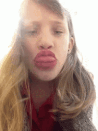 a woman is making a funny face with her big red lips .