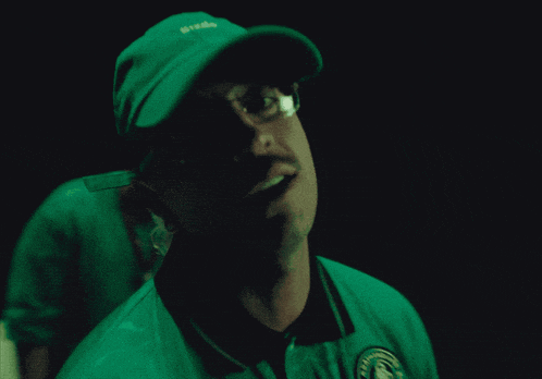 a man wearing glasses and a green hat with the word lacoste on it