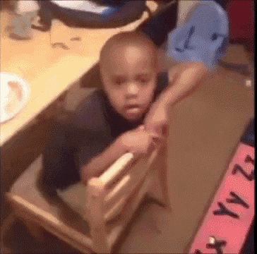 a young boy is sitting in a wooden chair next to a sign that says yyz