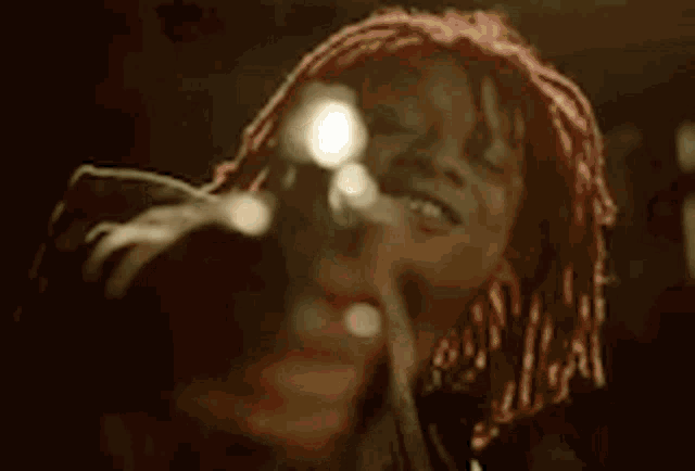 a woman with dreadlocks is singing into a microphone in a dark room .