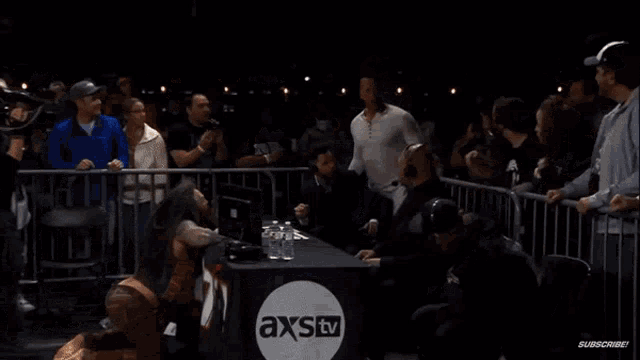 a man kneeling down in front of a table that says axstv on it