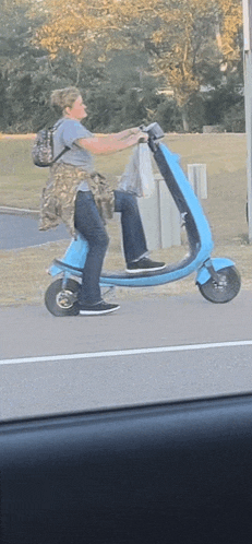 a person is riding a blue scooter on a street