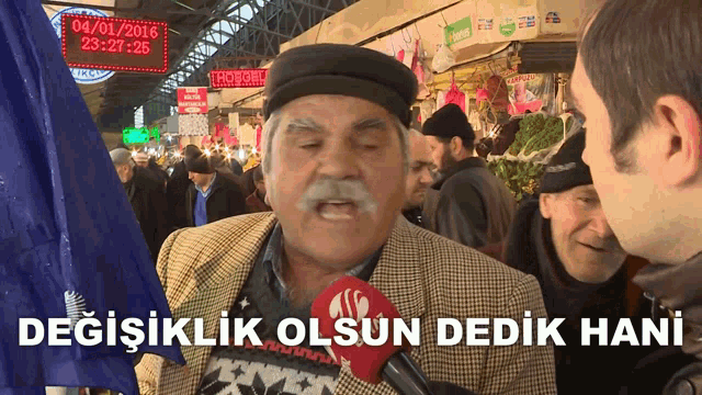 a man with a mustache is talking into a microphone with the words degisiklik olsun dedik hani written below him