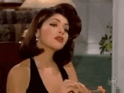 a woman in a black dress and earrings is holding a glass of wine .