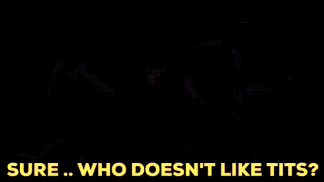 a man in a suit and tie is sitting in a dark room with the words " sure who does n't like tits " below him
