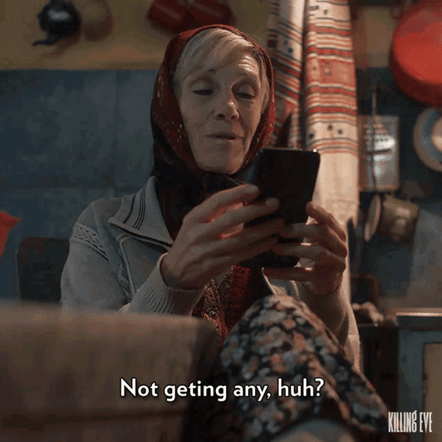a woman with a scarf around her head is looking at a cell phone and says not getting any huh