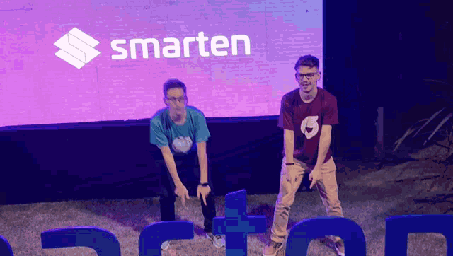 two men stand in front of a smarten sign