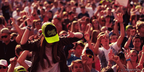 a woman in a crowd wearing a cap that says everybody loves a hippie