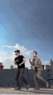 two men are dancing in front of a blue sky with viggle.al written on the bottom right