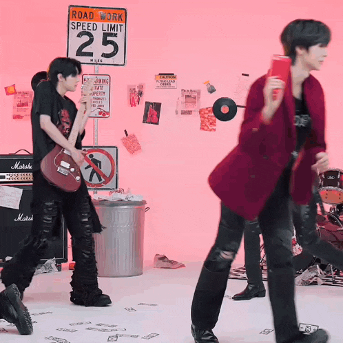 a man playing a guitar in front of a sign that says roadwork speed limit 25 miles