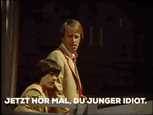 a man and a girl are standing next to each other and the words jetzt hör mal du junger idiot are on the screen