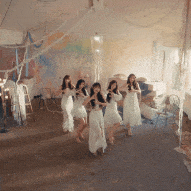 a group of young women in white dresses are dancing together