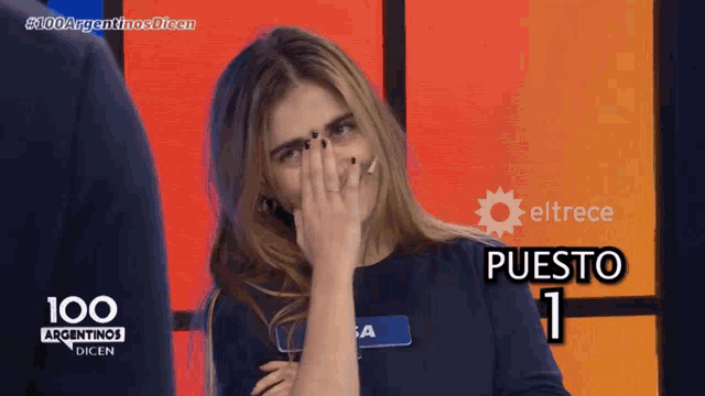 a woman covering her face with her hand in front of a sign that says puesto