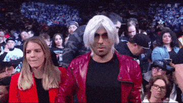 a man wearing a wig and a red jacket stands in a crowd of people