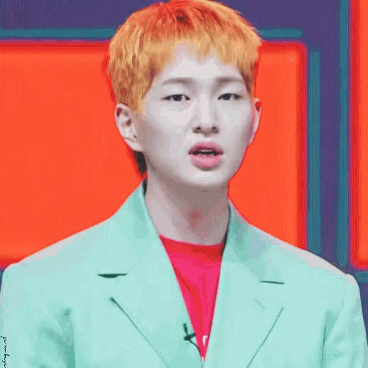 a man with yellow hair is wearing a green jacket and a pink shirt