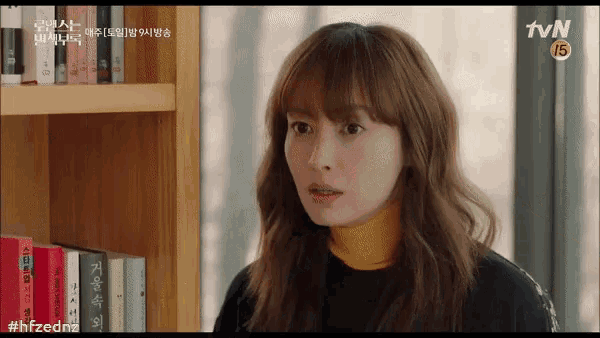 a woman sitting in front of a bookshelf with tvn written on the bottom right corner