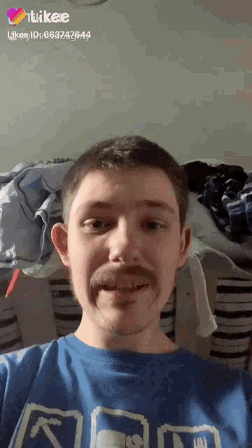 a man with a mustache is wearing a blue shirt that says likee on the bottom