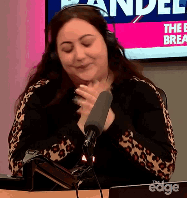 a woman wearing headphones sits in front of a microphone in front of a screen that says " the break "