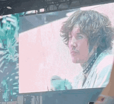 a man with curly hair is being shown on a screen