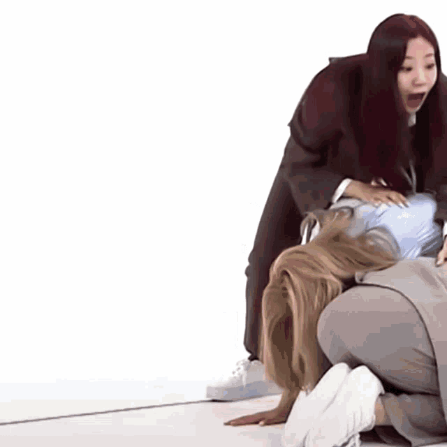 a woman is kneeling on the floor while another woman stands behind her