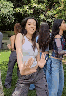 a group of young women are standing in the grass dancing together .