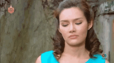 a woman in a blue dress is making a face with her eyes closed .